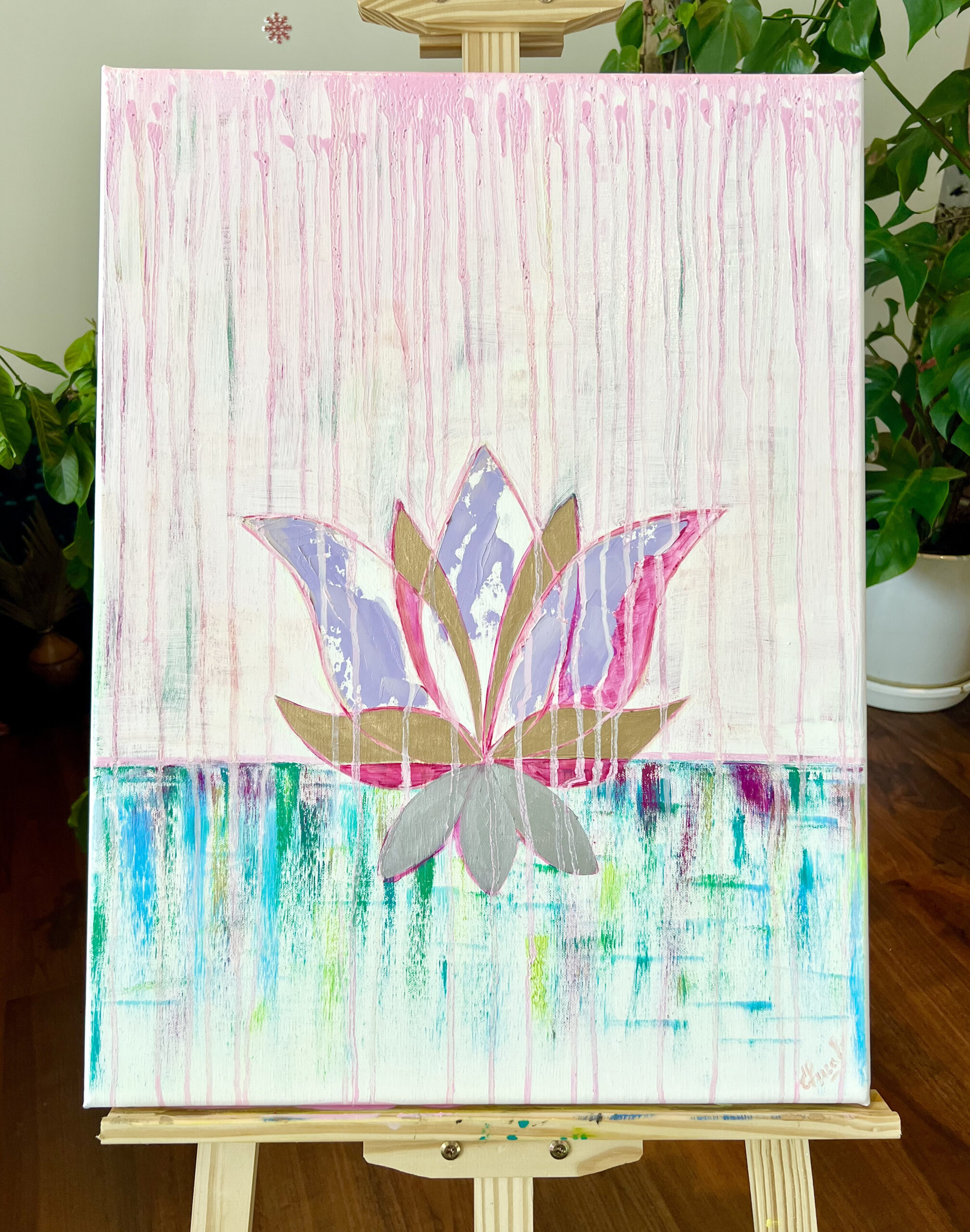 Golden Lotus oil painting by Lana Swan on a wooden easel beside green house plants