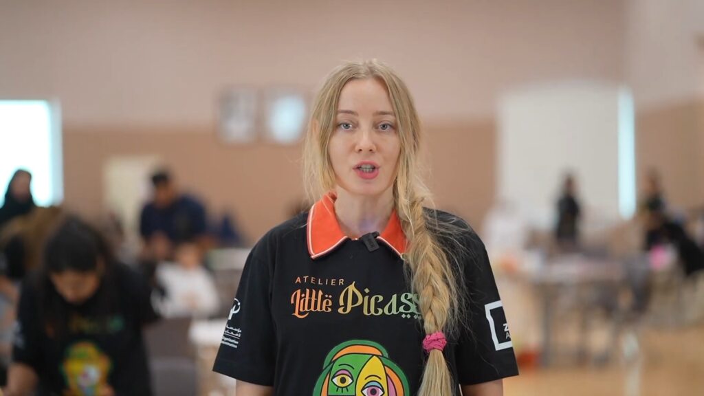 Lana Swan giving an interview at Atelier Little Picasso in Abu Dhabi, wearing the event T-shirt