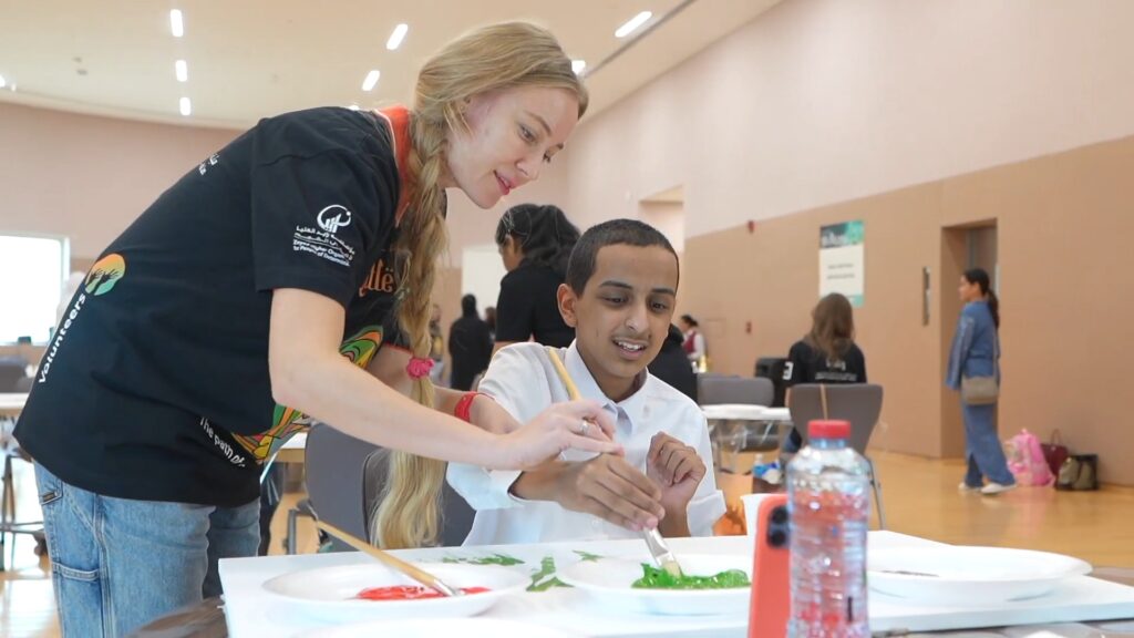 Lana Swan helping a young student paint at Atelier Little Picasso in Abu Dhabi